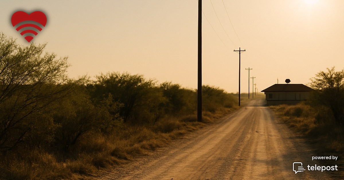 A rural road at dusk with a single utility pole strung with cable, fading into open country while a distant city glows on the horizon.